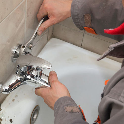 A Plumber Repairs a Bathtub Faucet.